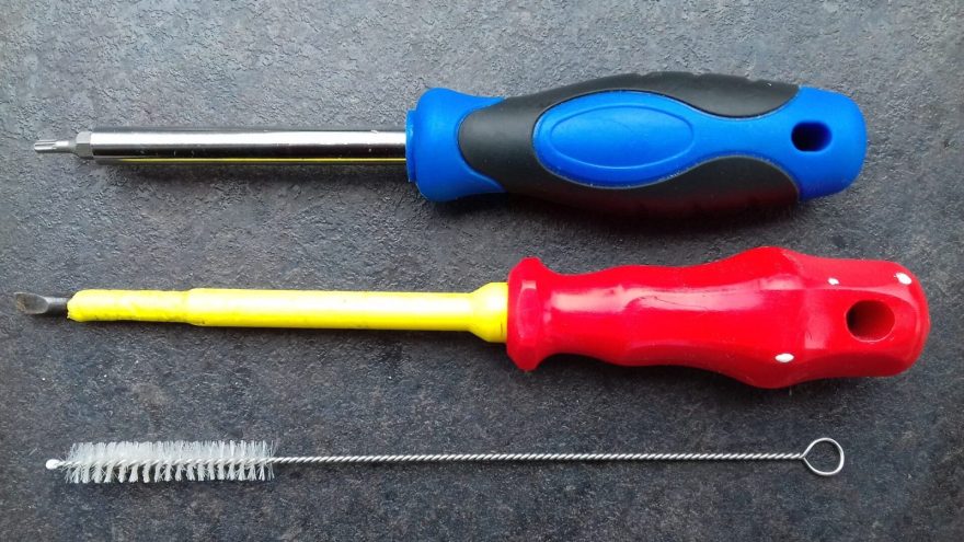 Hands repairing a device with tools on a workbench
